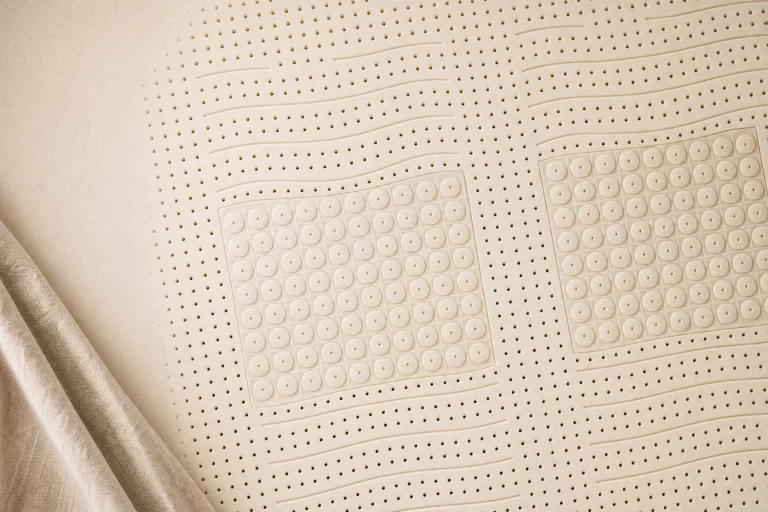 Superficie cenital de un colchón de látex 100% natural con perforaciones de ventilación y zonas de firmeza, en tono beige natural